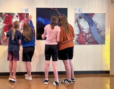 Four seventh-graders look at large satellite images displayed at the Community Engagement Center